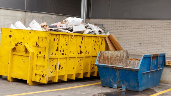 A large and small skip filled with a variety of waste 